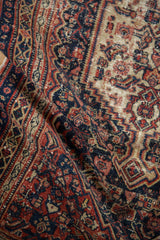 Antique Senneh rug's Herati motif and serrated patterns, with time-softened red and navy pile.