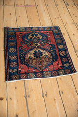 Angled view of an antique Malayer square rug mat with double medallions and a floral border.