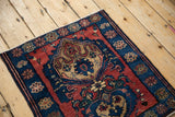 Perspective view of an antique Malayer mat's deep sapphire blue border and madder red field.