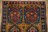 Detail of a Farahan Sarouk rug's blue and red scrolling motifs against a dusty gold field.