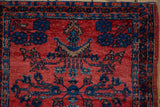 Corner detail of an antique Sarouk mat showing intricate floral bouquets in ruby and sapphire.