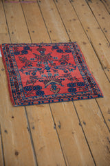 Angled view of an antique German Sarouk sampler rug with a ruby red field and sapphire blue details.