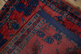 Detail of the antique Sarouk rug's back, showing the hand-knotted weave and stitched navy fabric edge.