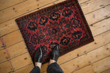 A person's view looking down on a vintage Sarouk rug in raspberry red.