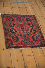 Angled view of a vintage Sarouk rug with pictorial navy motifs on a raspberry red field.