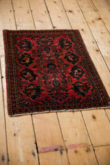 Vintage Sarouk Persian rug with a raspberry red and navy blue floral pattern, shown at a high angle.