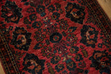 The worn, hand-knotted texture of a vintage Persian Sarouk rug in raspberry red and navy blue.