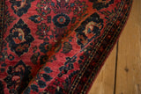 Folded corner of a vintage Sarouk rug showing its rich raspberry red pile texture.
