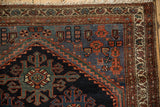 Corner detail of vintage Mehreban rug, featuring trefoil guls, animal motifs, red and navy borders.