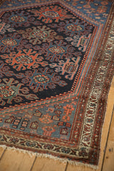 Vintage Mehreban rug detail with worn navy field, geometric guls, and multi-band red and ivory border.