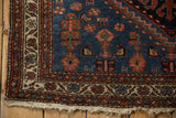 Vintage Mehreban rug corner featuring navy field, patterned borders, and secured threadbare fringe.