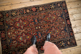 A perspective view of an antique Farahan Sarouk rug, showing its intricate floral design underfoot.