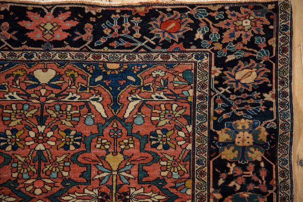 Detailed floral palmettes in the navy blue border of a fine antique Farahan Sarouk rug.