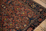 Corner view of an antique Farahan Sarouk showing the navy border palmettes and madder red field.