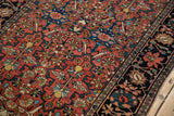 Intricate palmettes on the madder red field and navy border of a fine antique Farahan Sarouk rug.