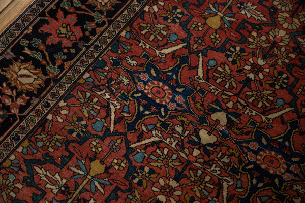 Close-up of the intricate floral patterns and navy border on an antique Persian Farahan Sarouk rug.