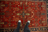 Overhead view of a vintage Sarouk rug with sprawling floral sprays on a brick red field.