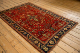 Angled view of a vintage Sarouk rug, highlighting the rich texture of its traditional red and navy design.