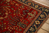 Ornate palmette and serrated leaf details in the navy blue border of a vintage Sarouk rug.