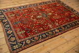 Vintage Sarouk rug viewed from an angle, showcasing its full design with a cherry red field and navy border.