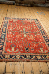 Angled view of a vintage Sarouk rug showing its sprawling floral pattern and navy border.