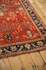 Angled view of a vintage Sarouk rug's navy border with palmette motifs beside the red field.