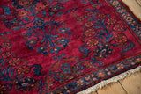 Ruby red field with blue scrolling floral sprays and narrow patterned border with fringe.