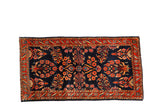 Antique Mohajeran Sarouk rug with allover floral sprays in red and gold on a dark navy blue field.