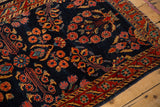 Detailed floral sprays in red and gold over the cobalt blue field of an antique Sarouk rug.