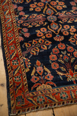 The intricate floral border and navy blue field of an antique Persian Mohajeran Sarouk rug.