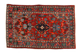Vintage Persian Bijar rug with a central shield medallion on a cherry red field of roses and vines.