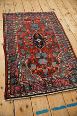 Vintage Persian Bijar rug from an angle, showing its navy medallion and cherry red field.