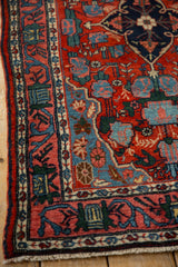 Close-up on the vintage Bijar rug's main border with a floral arabesque vine in red and blue.