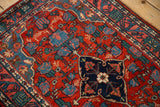 Close-up of a vintage Bijar rug's navy medallion corner and red field with blue floral vines.