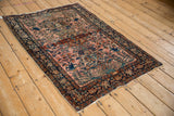 Angled perspective of an antique Farahan Sarouk rug showing complex arabesques and a central medallion on a fuchsia ground.