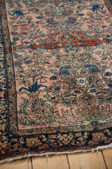 Angled view of a fine antique Farahan Sarouk rug's corner, showing the time-softened pile and intricate floral border.