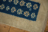 Vintage distressed Oushak rug showing geometric cobalt starburst motif, visible pile wear, and intact selvage.