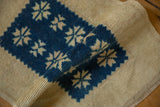 Rolled vintage distressed Oushak rug pile with indigo geometric starburst pattern.