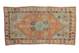 A vintage distressed Oushak runner with a geometric floral medallion in soft rust and mint green.