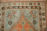 Close-up of the distressed Oushak rug's border with floral motifs in terracotta, mint green, and chocolate brown.