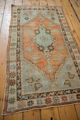 Vintage Oushak rug runner from an angle, showing the distressed terracotta and slate blue pattern.