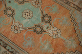 Worn, low-pile texture of a vintage Oushak rug with floral motifs in mint green and terracotta.