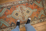 Distressed vintage Oushak runner with pale burnt orange and mint green shield medallion, underfoot.