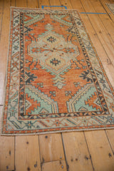 Distressed Oushak runner corner with soft orange, mint green, and serpent starburst motifs.