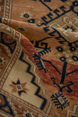 Low, even pile of a distressed Turkish rug showing geometric hook motifs in navy, copper, and ivory.