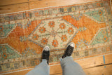 Textural distressed Oushak runner featuring worn terracotta, pale turquoise, and germinating blossoms.