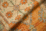 Folded vintage distressed Oushak rug showing terracotta, platinum, and mint floral pile texture.