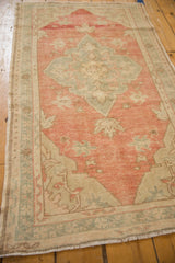 Angled view of a distressed Turkish Oushak rug showing its soft rose and slate blue palette.