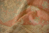 The hand-knotted texture of a distressed Oushak rug with rose, seafoam green, and beige abrashes.