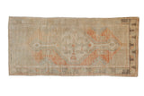 Distressed Oushak runner with a time-softened diamond medallion in pale orange, sandalwood, and soft green.
